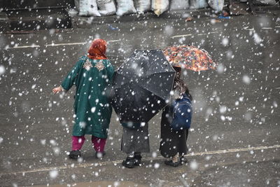 People with umbrella standing on road during snowfall