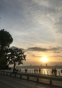 Silhouette people by tree against sky during sunset