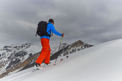 Low angle view of man skiing on snow covered mountain against sky