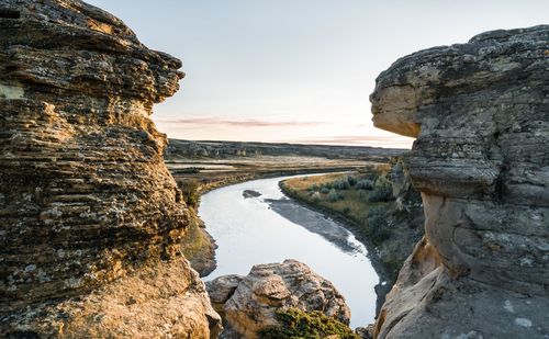 Scenic view of river and rock formation against sky during sunset