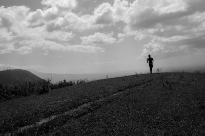 Man walking on field against sky