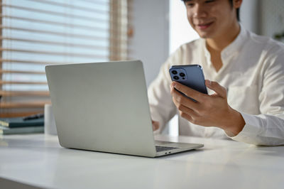 Young woman using mobile phone on table