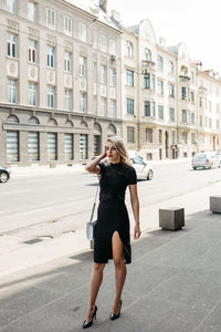 Fashionable woman standing against buildings in city