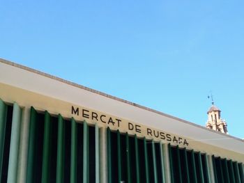 Low angle view of text on building against clear blue sky