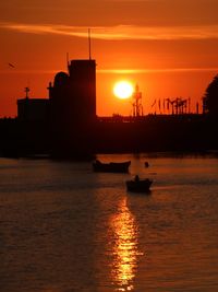 Silhouette ship in sea against orange sky