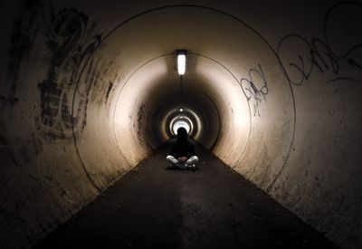 Rear view of woman walking in tunnel