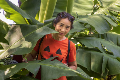 Portrait of smiling senior woman standing amidst plants