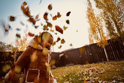 Cute girl throwing dry leaves during autumn