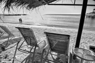 Chairs on beach against sky