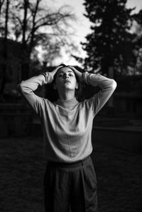 Portrait of young woman standing against tree