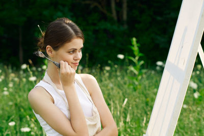 Young woman looking away while standing outdoors