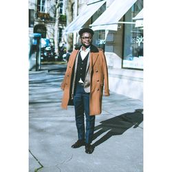 Full length portrait of young man standing on footpath