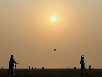 Silhouette people playing against clear sky during sunset