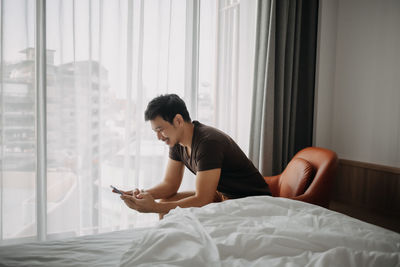 Young woman sitting on bed at home
