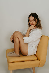 Young woman sitting on sofa against white background