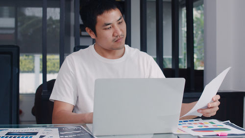 Young man using mobile phone at table