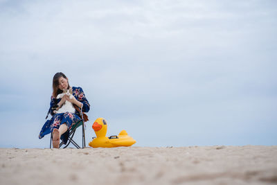 Woman relax sit on beach chair and hug her cat on sand beach