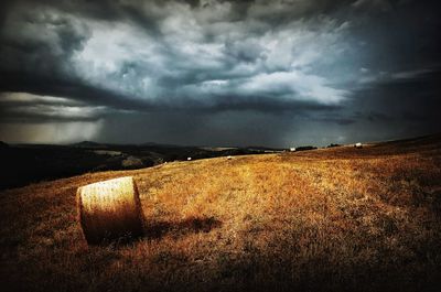 Scenic view of field against storm clouds