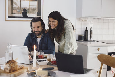 Smiling mature couple using laptop at home