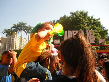 Rear view of people with balloons against sky