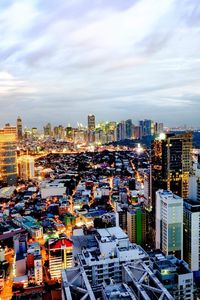 Illuminated cityscape against cloudy sky