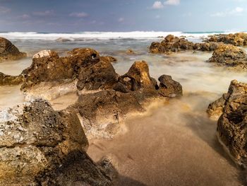 Scenic view of rocks on beach against sky