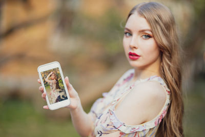 Portrait of beautiful woman showing mobile phone