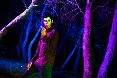 Portrait of young woman standing on purple at night