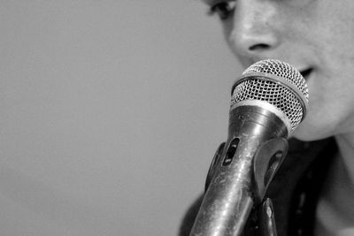 Close-up of young woman with microphone against wall