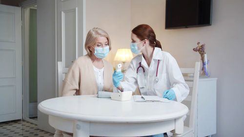 Doctor wearing mask checking patients temperature