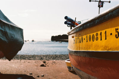 Close-up of yellow ship moored on beach against sky