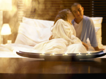 Young couple romancing while sitting on bed at home