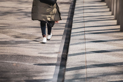 Low section of woman walking on footpath