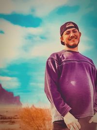 Portrait of young man standing against sky