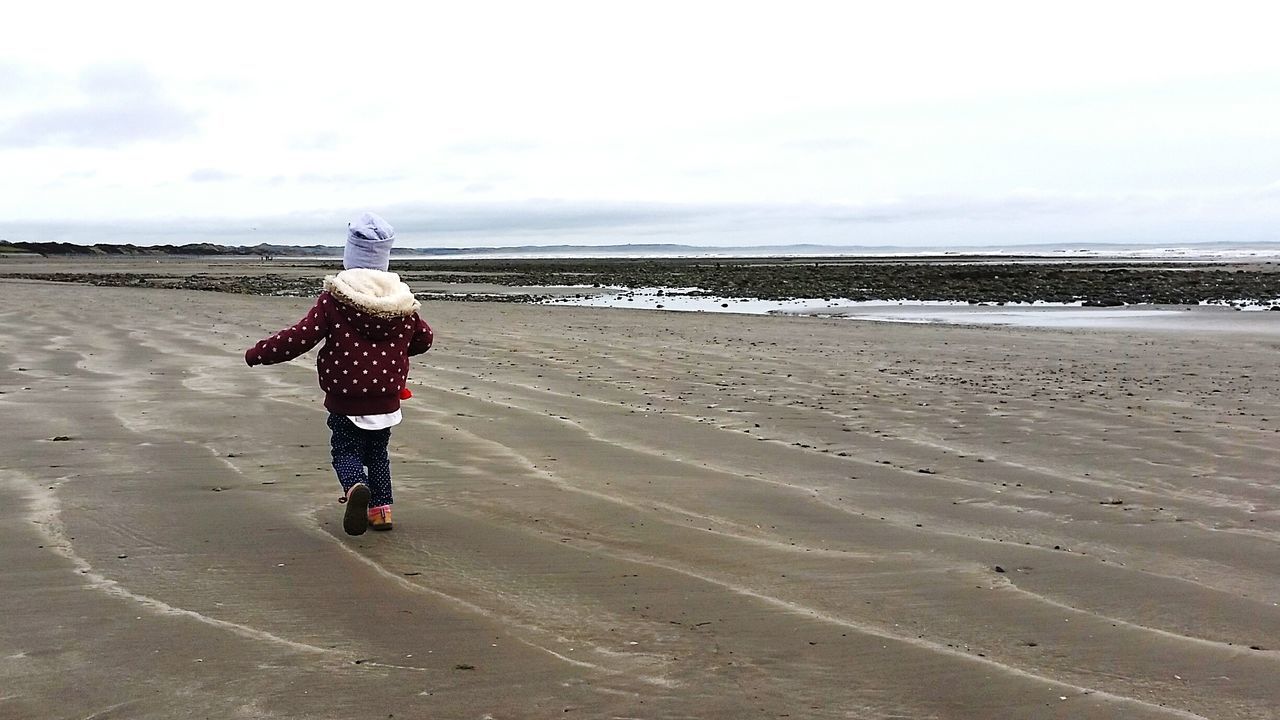 full length, sand, rear view, beach, lifestyles, leisure activity, casual clothing, walking, sky, childhood, shore, standing, day, tranquility, nature, boys, tranquil scene, outdoors