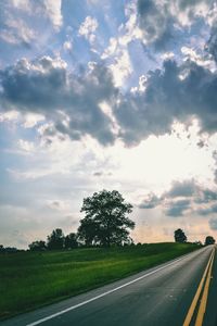 Empty road amidst field against sky