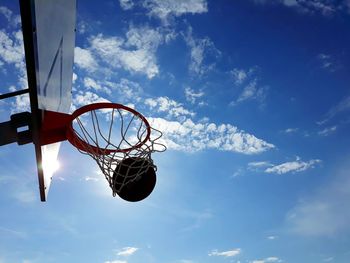 Low angle view of basketball in hoop against blue sky
