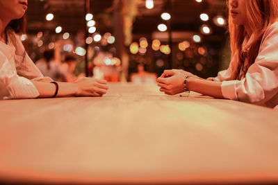 Midsection of women sitting at table