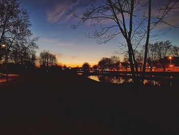 Silhouette trees by lake against sky during sunset