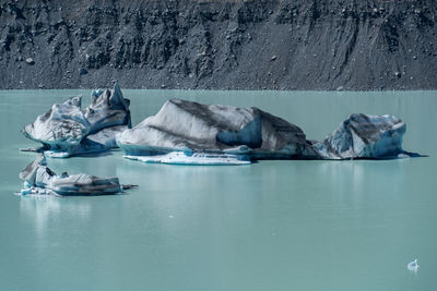 Icebergs floating on lake against mountain