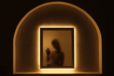 Silhouette of a woman against the light, behind glass