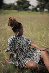 Side view of woman sitting on field