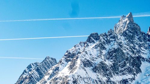 Low angle view of snowcapped mountain against blue sky