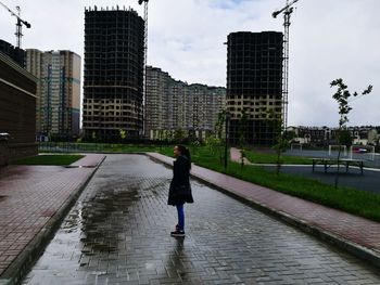 Rear view of woman walking on water in city against sky