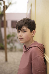 Portrait of a teenage boy leaning against wall looking camera