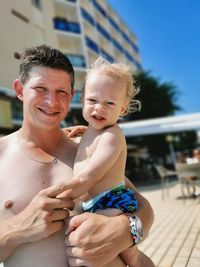 Portrait of happy father carrying son outdoors