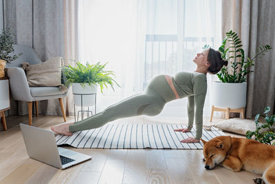 Pregnant female doing prenatal yoga at home in the brightly living room