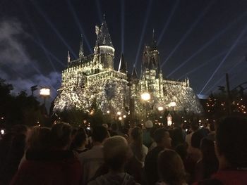 Crowd at illuminated city against sky at night