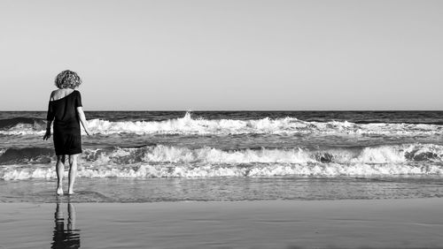 Woman looking at sea against clear sky