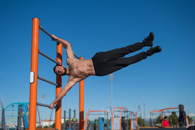 Low angle view of young man exercising against sky